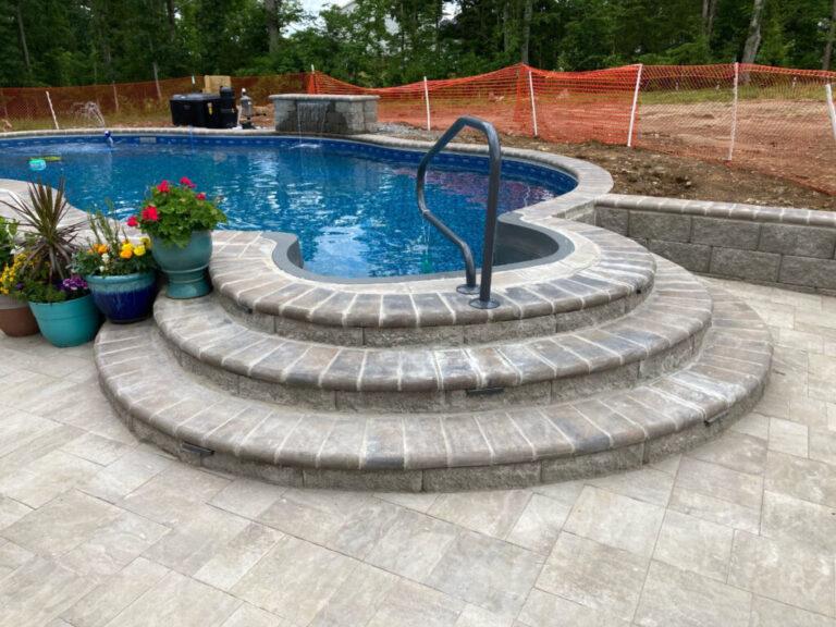 semi inground pool with decking and landscaping in backyard