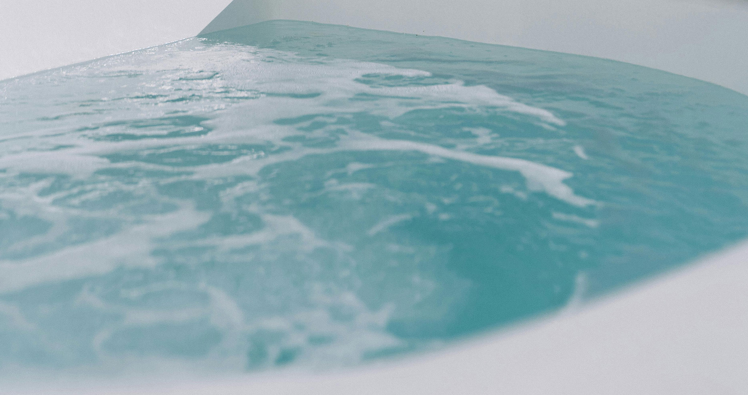 Aerial view of turquoise water with white foam forming gentle waves on the surface.
