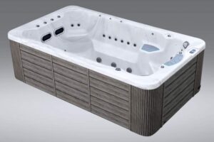 White rectangular hot tub with multiple jets and wood-panel exterior for outdoor use.