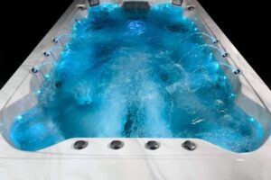 White hot tub filled with bright blue water, jets active along the sides, viewed from above.