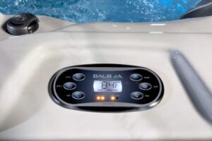 Balboa hot tub control panel with a digital display and orange indicator lights on a cream-colored surface.
