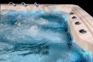 Close-up of a hot tub with bubbly blue water and metal jet nozzles along the rim on the right side.