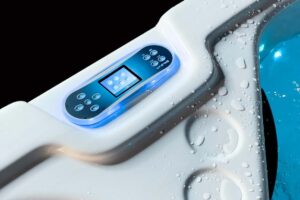 Control panel on a white hot tub with blue lighting, surrounded by water droplets