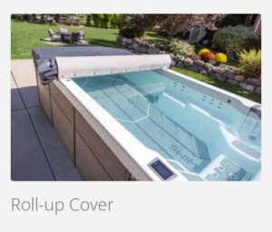 Roll-up cover retracted on a rectangular outdoor hot tub with a wooden deck and garden in the background.