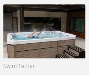 Person swimming in an outdoor rectangular hot tub with wood-paneled sides and steps nearby.