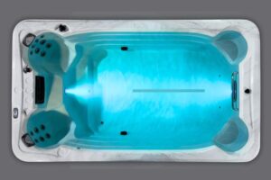 Top-down view of a white hot tub filled with blue-lit water, showing built-in seats and jet outlets