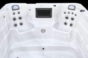 Top view of a white hot tub interior featuring multiple circular water jets on both sides and a central drain, ready for use.