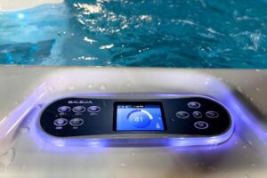 Balboa hot tub control panel with a blue-lit display showing 81, set in a tub with water droplets on the surface.