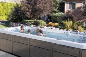 Group of people relaxing and chatting in a hot tub in a sunny backyard garden.
